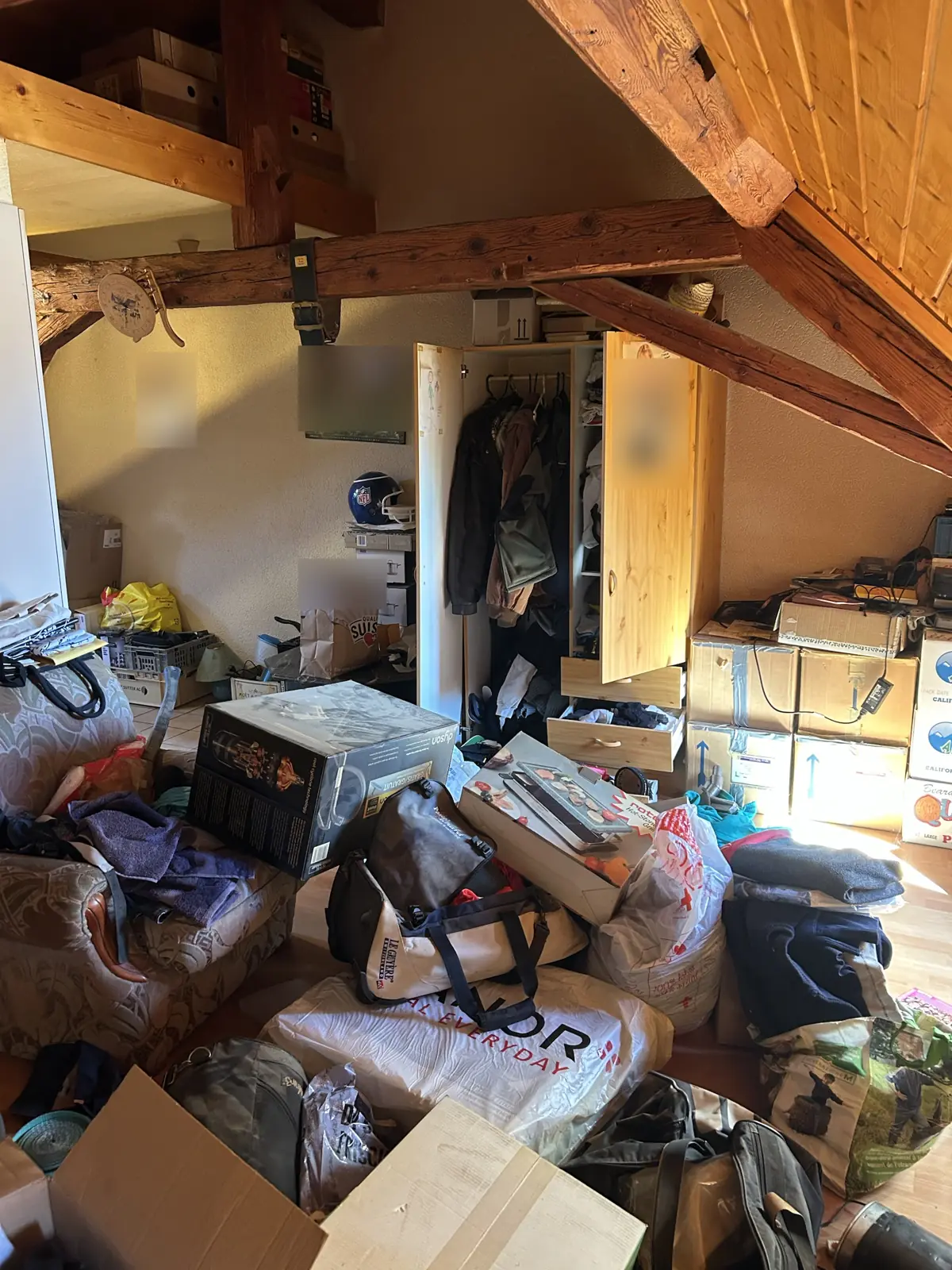 Combles sous charpente encombrés de sacs, cartons et vêtements avant débarras à Bulle