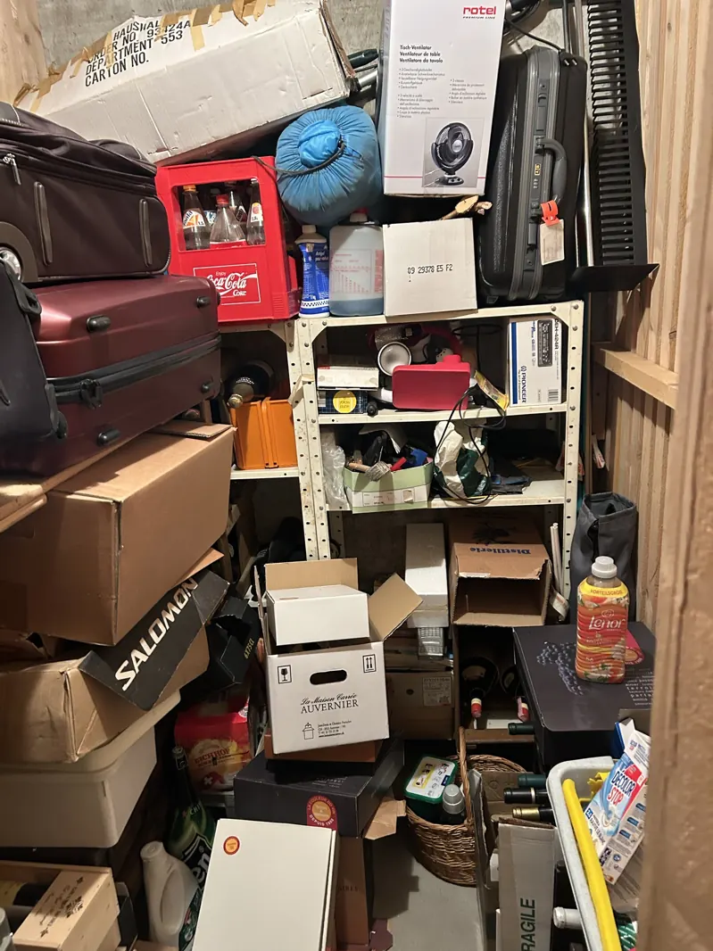 Cave encombrée de valises, caisses et cartons avant débarras en Gruyère