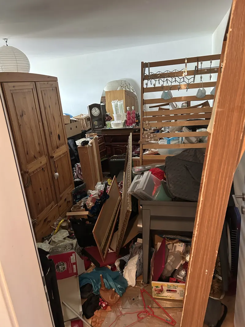 Chambre encombrée de meubles, cadres et cartons avant débarras à Fribourg