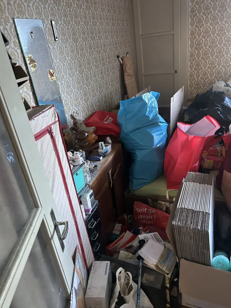Chambre encombrée de sacs, cartons et objets avant débarras à Bulle